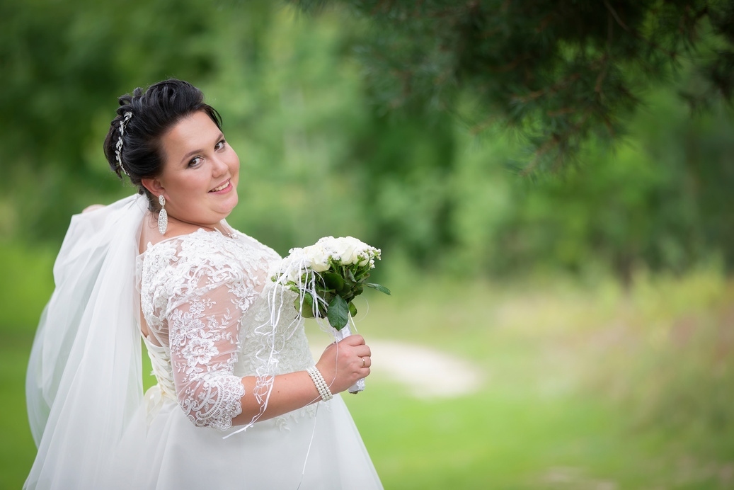 Fat bride with a wedding bouquet on a summer background.